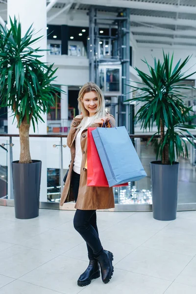 Blonďatá Mladá Dáma Hnědém Plášti Nákupním Středisku Pozadí Butiků Dívá — Stock fotografie