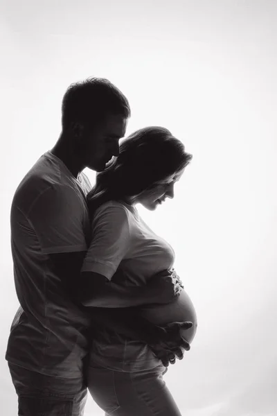惊人的孕妇凝视着肉感 丈夫站在妻子身后抱着她的肚子 父母和婴儿的概念 — 图库照片