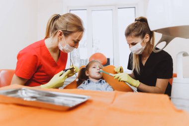 Kadın dişçiler kızı iyileştirme prosedürüne hazırlıyorlar.