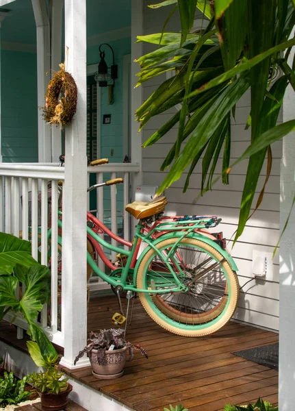 Renkli bisiklet tropikal bitkiler ile bir ada tarzı evin rahatlatıcı bir ön verandada oturan