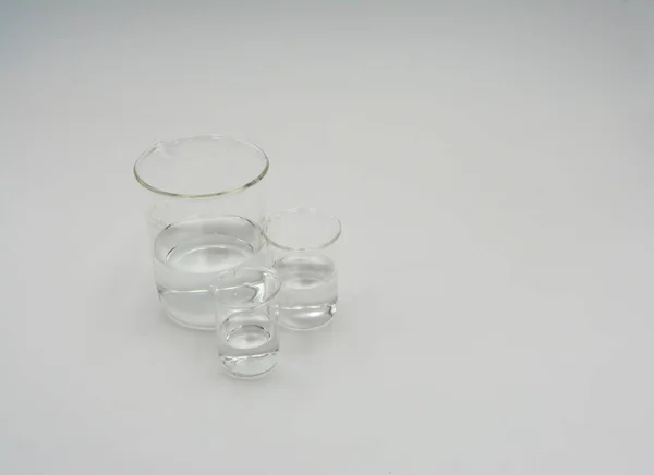 Görüntünün sol tarafında berrak su ile üç yuvarlak bilim behers birlikte gruplanmış