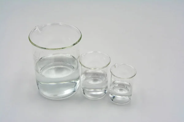 Görüntünün ortasına yerleştirilen beyaz bir arka plan üzerinde, net su ile üç yuvarlak bilim behers üzerinde deending boyut sırasına dizilmiş