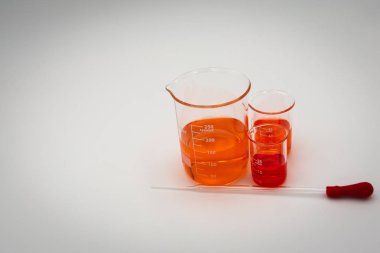 Üç bilim beherturuncu ve kırmızı sıvı ile kırmızı bir ampul ile bir damlalık ile beyaz bir arka plan üzerinde ekranın sağ tarafına ayarlanmış dolu