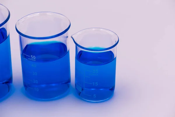 Beyaz bir arka plan üzerinde ekranın sağ tarafına turuncu ve kırmızı sıvı seti ile dolu üç bilim gagaları