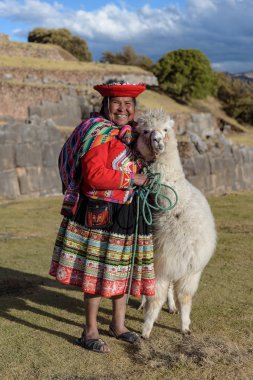 Cuzco, Peru - 14 Temmuz 2018. Sacsayhuaman, Cusco, Peru, Güney Amerika'da alpaka / lama ile geleneksel renkli giysiler giymiş Perulu kadın.