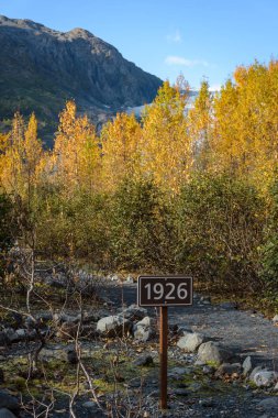 Exit Glacier davasında 1926'yı imzalayın. Buzulun 1926'da nerede olduğunu gösteriyor. İklim değişikliğine bağlı buzul durgunluğun görünür bir göstergesidir. Kenai Fjords National Park, Seward, Alaska, Amerika Birleşik Devletleri