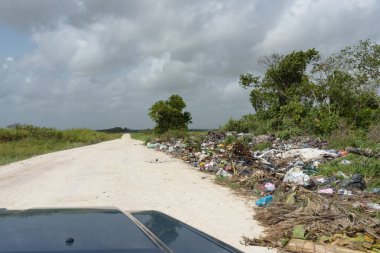 Orange Walk, Belize - 21 Mayıs 2017: Yolun kenarına atılan çöp öğütücüsü Latin Amerika 'daki yol kenarı çöp öğütücüsü sorununu vurguluyor. Kapüşonlu arabanın ön camından bak.