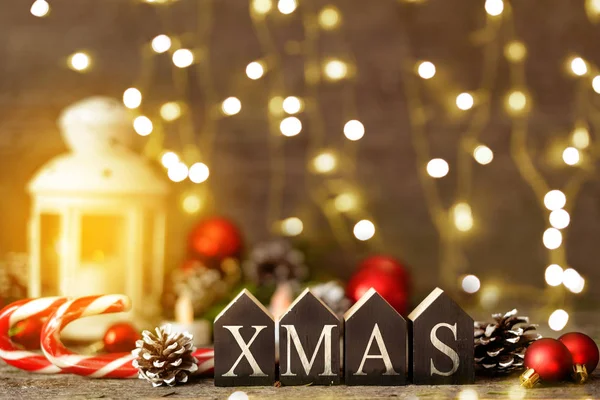 Vánoční složení s a zářící světla. Červené koule, šišky, lízátko, hračka domů textu Vánoce na dřevěný stůl — Stock fotografie