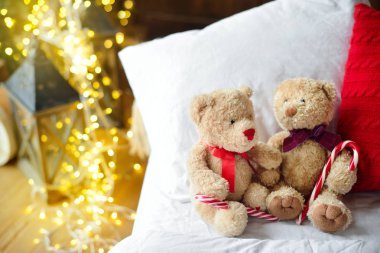 İki oyuncak ayılar ile Noel ağacı yakınındaki kırmızı candys yatağa siting.