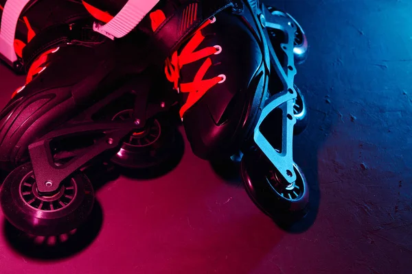 Neon mavi sagenta pembe ışık koyu grunge arka plan üzerinde paten inline paten veya rollerblading yakından görünümü — Stok fotoğraf