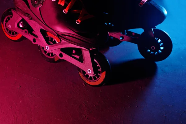 Neon mavi sagenta pembe ışık koyu grunge arka plan üzerinde paten inline paten veya rollerblading yakından görünümü — Stok fotoğraf