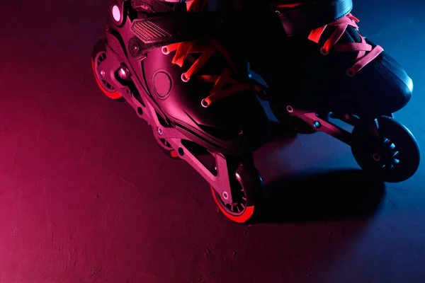 Z bliska widok rolek inline skate lub rolkach na ciemnym tle grunge w kolorze Neon Blue magenta różowy światła — Zdjęcie stockowe