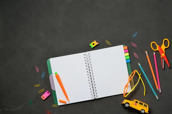 Concepto de regreso a la escuela: libro abierto con material de oficina y material para estudiantes sobre fondo de tiza negra. Espacio para texto . — Foto de Stock