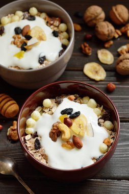 Granola yougurt, fındık, ahşap kahverengi arka plan üzerinde kurutulmuş meyve ile
