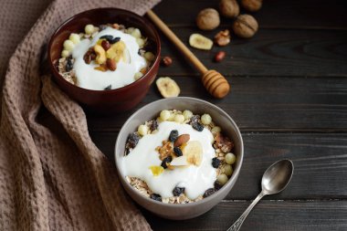 Granola yougurt, fındık, ahşap kahverengi arka plan üzerinde kurutulmuş meyve ile