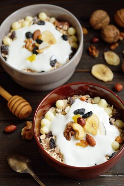 Süt, fındık, ahşap kahverengi arka plan üzerinde kurutulmuş meyve ile Müsli