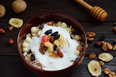 Süt, fındık, ahşap kahverengi arka plan üzerinde kurutulmuş meyve ile Müsli