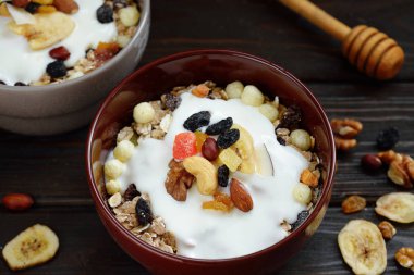 Süt, fındık, ahşap kahverengi arka plan üzerinde kurutulmuş meyve ile Müsli