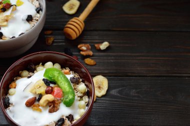 Süt, fındık, ahşap kahverengi arka plan üzerinde kurutulmuş meyve ile Müsli