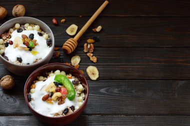 Süt, fındık, ahşap kahverengi arka plan üzerinde kurutulmuş meyve ile Müsli