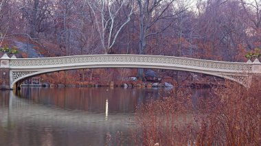 Sessiz gündoğumu yay köprüde Central Park, New York City'de. En büyük yaya köprüsü urns ekerek dekore edilmiş Park Manhattan binalar arka plan ile muhteşem görünüyor.
