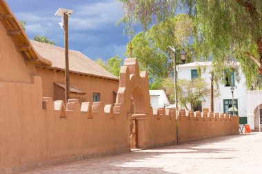 Gıda San Pedro de Atacama Çölü Kilisesi'nin farz küçük bir kare. Bir haç ve ayrıntılı kırmızı kil çit güzel güneşli bir günde bir kilise kapısı.