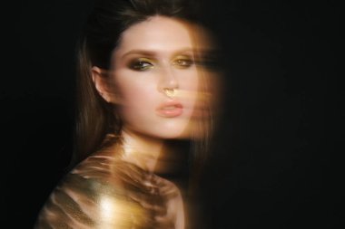Güzellik yakın çekim. inanılmaz genç model yeşil dumanlı göz makyaj ile. yaratıcı moda bakmak. esmer siyah izole. Boynundaki altın boya. sahte burun piersing