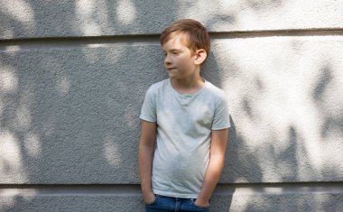 7 yaşındaki çocuğun açık hava portresi. beyaz t-shirt ve kot pantolon çocuk. gündelik kıyafetler giyen çocuk. gri arka planda kafkas çocuk. ciddi çocuk