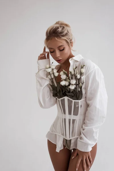 若い美しい金髪の女が目を閉じた ファッション ポートレート 白いブラウスと白いコルセットベルトの女性 流行の服 お花のある女性 優しさの概念 — ストック写真