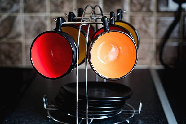 Разноцветные чашки и черные тарелки на держателе — стоковое фото
