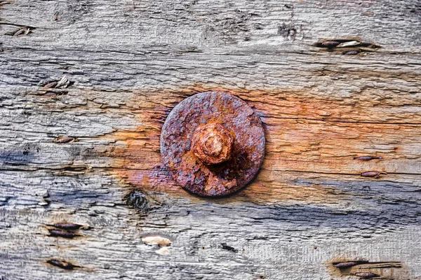 Corroded nut with washer in a wooden surface — Stock Photo, Image