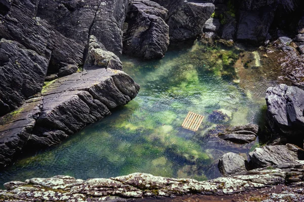 Деревянный поддон в воде на скалистом побережье острова Дурси — стоковое фото