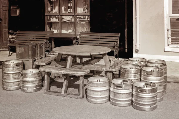 Barris de cerveja de alumínio na mesa e bancos perto da casa — Fotografia de Stock