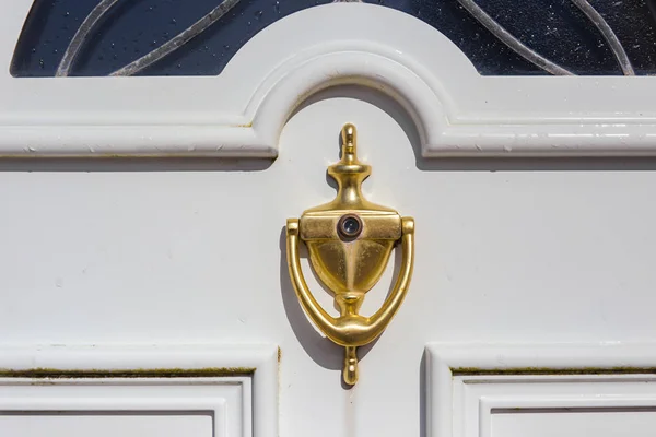 Golden door knocker med titthål på en vit dörr — Stockfoto