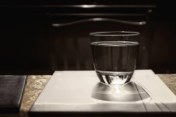 Bicchiere d'acqua sul tavolo con riflessi su di esso — Foto Stock