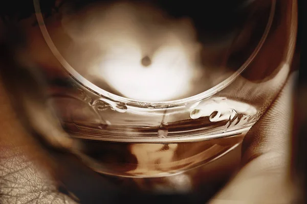 Kant av konjak glas med dryck i en hand — Stockfoto