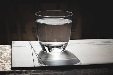 Üzerinde yansımaları olan masanın üzerinde bir bardak su