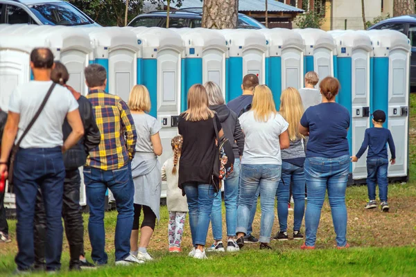 Groep mensen die in de buurt van draagbare toiletten staan — Stockfoto