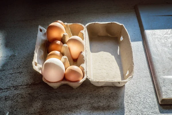 Картонный ящик с большими и маленькими яйцами на столе — стоковое фото