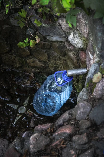 Натуральна весняна вода входить у блакитну пластикову пляшку — стокове фото