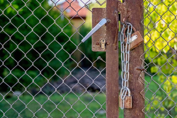 Ett lås och två hänglås på en gammal rostig grind. — Stockfoto