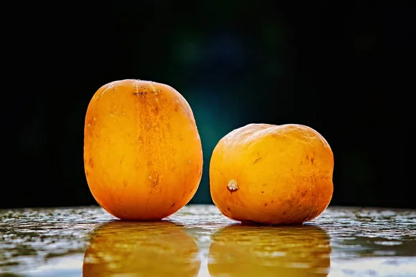 Two ripe True Lemon cucumbers on a wet surface — Stock Photo, Image