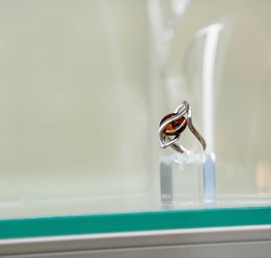 Bir cam raf üzerinde kehribar göz ile gümüş yüzük