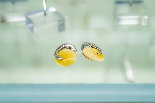 Two silver earrings with amber on a glass shelf — Stock Photo, Image