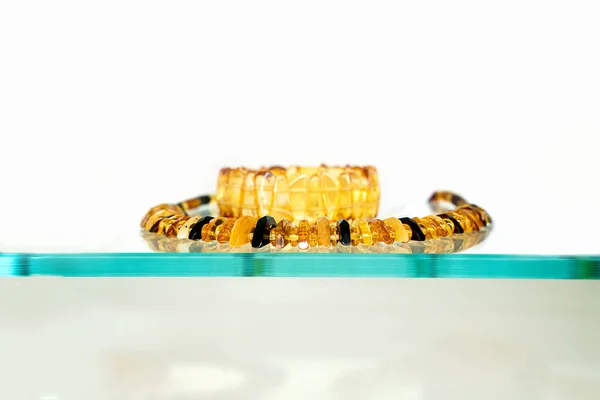 Amber neklace and bracelet on a glass shelf. — Stock Photo, Image