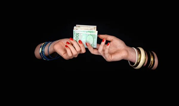 As mãos de duas mulheres com pulseiras passam um a outro o euro curren — Fotografia de Stock