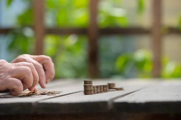 Money, coins, the grandmother on pension and the concept of life, minimum - hands of the old woman recalculate coins on a wooden table