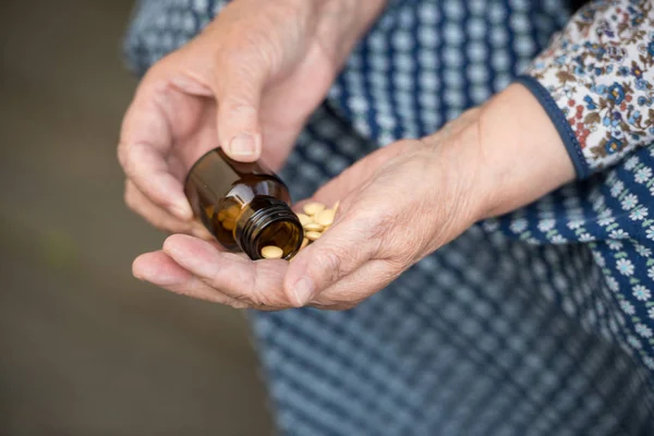 Pills, old age and health concept - pills in the hands of an old lady closeup