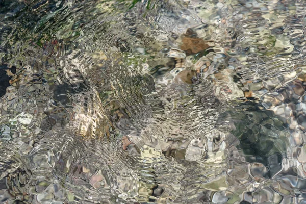 Ripples on the water, transparent river water and reefs - a natural texture