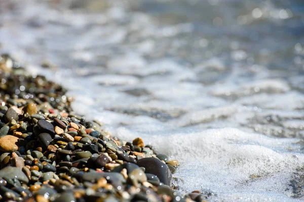 Wet pebbles and sea waves-the texture of the sea coast.